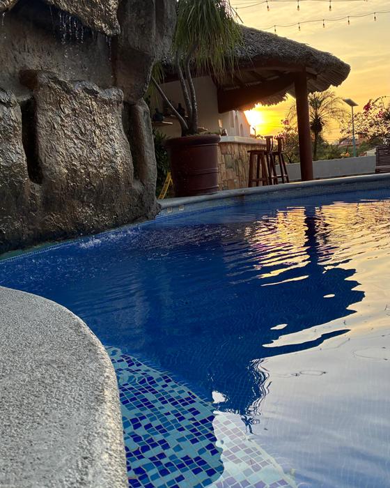 Pool with blue mosaic and waterfall at sunset