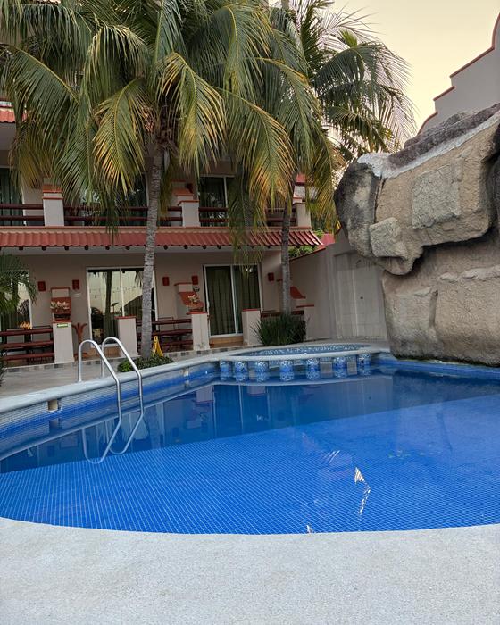 Hotel Bonito pool with palm trees and balconies at golden hour
