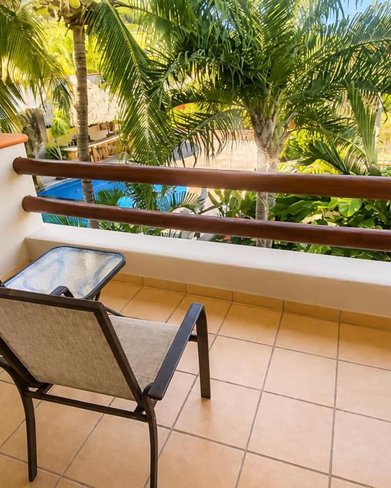 Balcony with chairs overlooking the pool and palms
