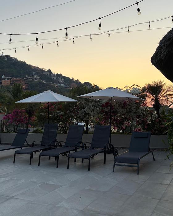 Terrace with loungers, umbrellas and string lights at sunset